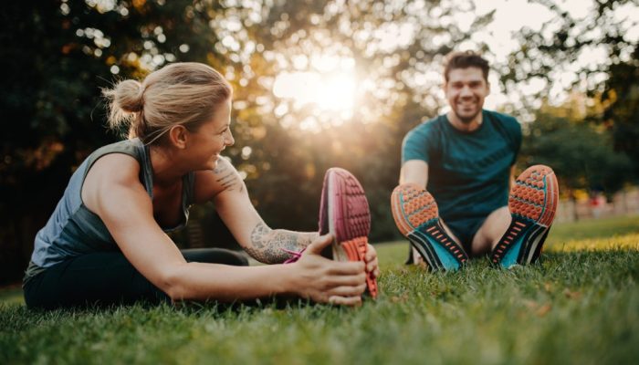 young-couple-doing-their-stretches-in-the-park-picture-id627761528